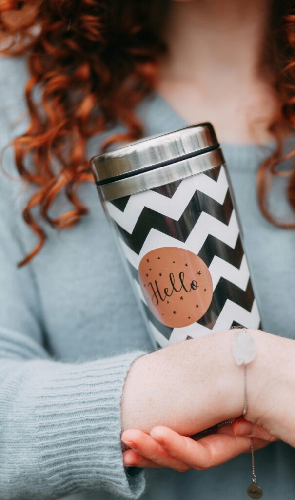 Close-up of a woman holding a chevron-patterned tumbler with 'Hello' text.